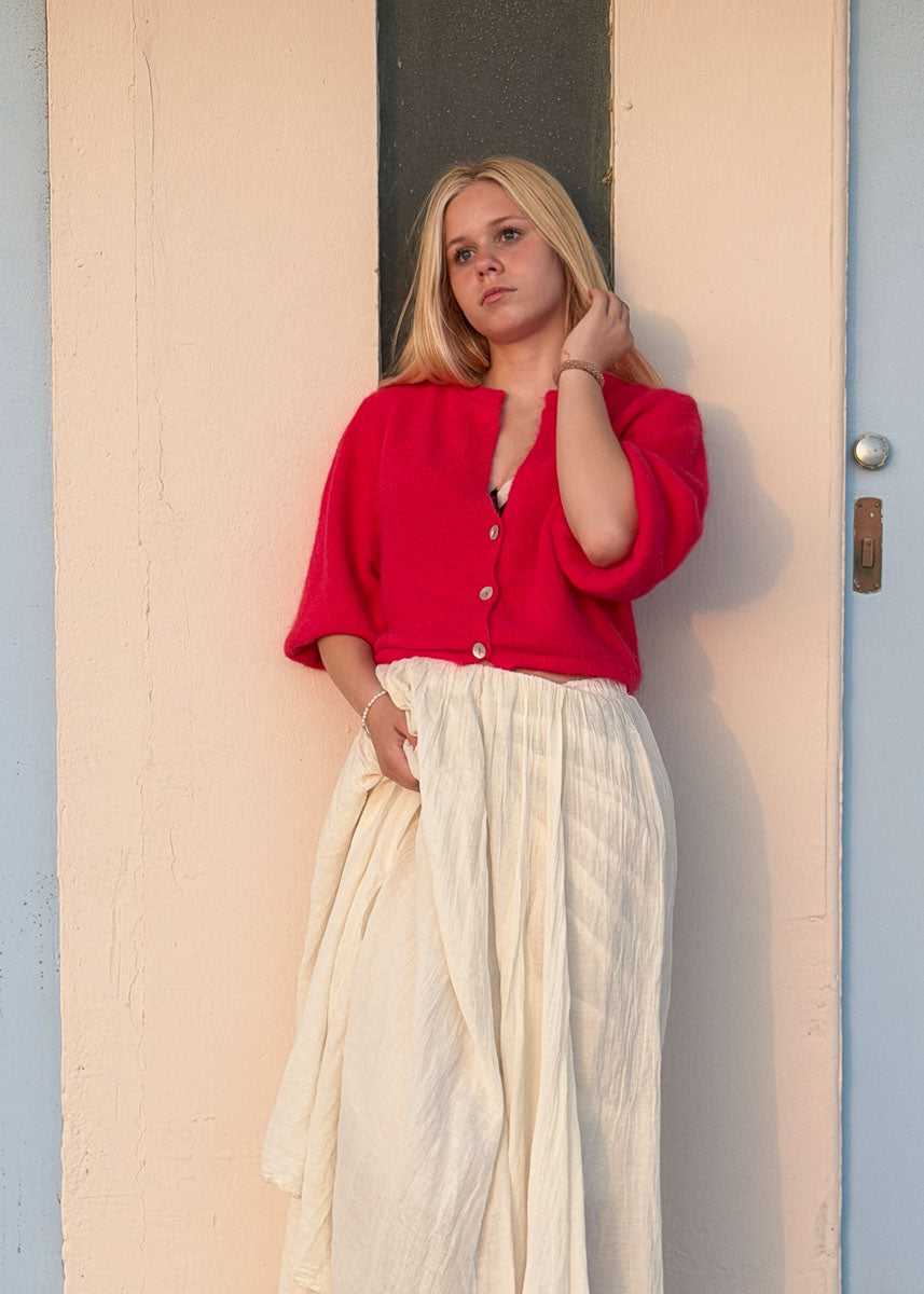 Gilet en maille mohair rouge femme à boutons nacrés, col en V, manches courtes légèrement bouffantes, coupe courte, vue de face en pied, allure balnéaire chic Dune & Coton — Couleur: Rouge Cerise