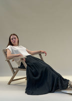 Jupe longue en voile de coton froissé noir femme portée assise, ampleur fluide et légère, esprit côtier Le Touquet-Paris-Plage Dune & Coton — Couleur: Noir