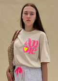 T-shirt femme en coton écru à imprimé Amore rose fluo et cœur jaune fluo, col rond, coupe ample, porté de face, esprit côtier Le Touquet-Paris-Plage Dune & Coton — Couleur: Beige