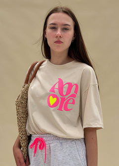 T-shirt femme en coton écru à imprimé Amore rose fluo et cœur jaune fluo, col rond, coupe ample, porté de face, esprit côtier Le Touquet-Paris-Plage Dune & Coton — Couleur: Beige