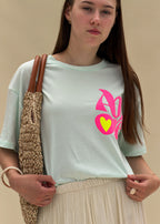 T-shirt femme en coton vert menthe à imprimé Amore rose fluo et cœur jaune fluo, col rond, coupe ample, porté de face, allure balnéaire chic Dune & Coton — Couleur: Vert d'eau