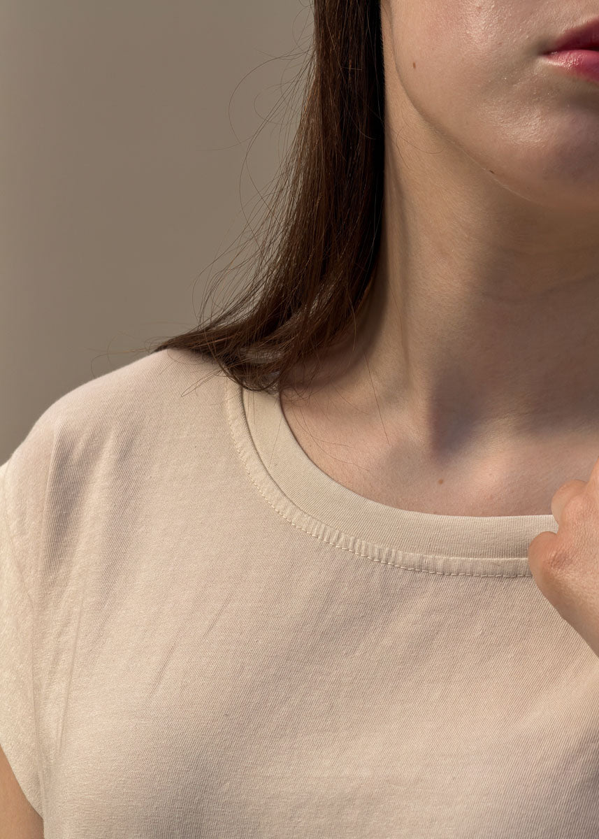 Détail du col rond et de la finition d'encolure surpiquée d'un t-shirt en coton crème femme, gros plan sur la maille jersey souple, Dune & Coton — Couleur: Crème