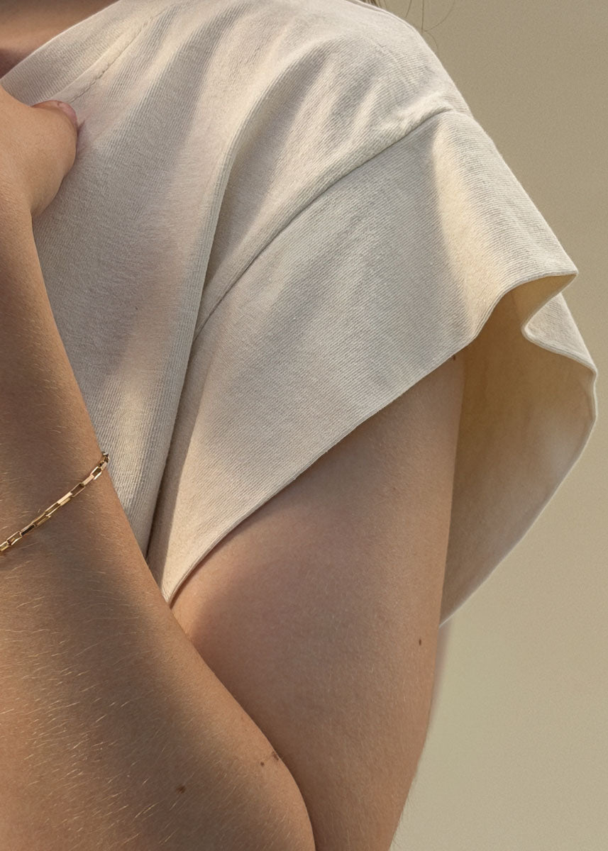 Détail de la manche courte tombante d'un t-shirt en coton crème femme, gros plan sur l'emmanchure et le tombé souple, Dune & Coton — Couleur: Crème